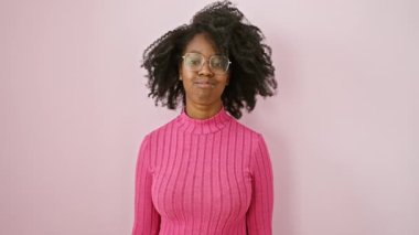 Komik Afro-Amerikalı kadın. Komik bir ifadeyle yanaklarını şişiriyor. Gözlük takıyor ve pembe bir odada duruyor.!