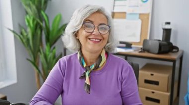 İş yerindeki güzel olgun kadın, gri saçlı ve neşe dolu, eliyle 