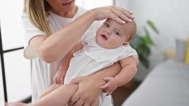 Anne evde kollarında kızıyla dikiliyor.