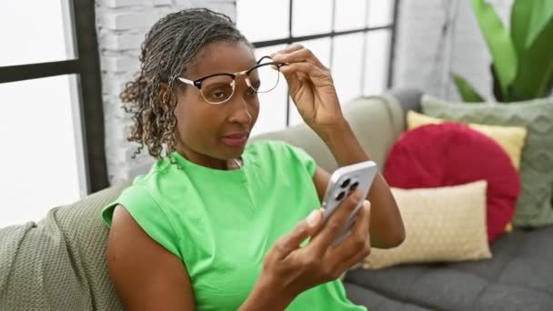 Femeie Africană Matură Surprins Citirea Textului Smartphone Timp Relaxează Canapeaua — Videoclip de stoc