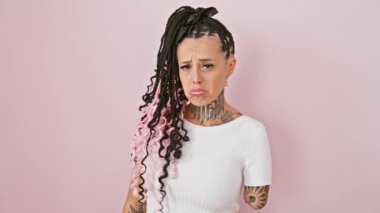 Endişeli, kızgın, ağlayan, yaralı kollu, üzgün, yalnız depresyonda yaşayan İspanyol bir kadın, pembe arka planda izole edilmiş bir acı portresi.