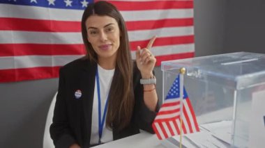 Genç, mutlu İspanyol kadın güven içinde Amerikan üniversite masasına işaret ediyor. Dostça gülümsemesi umut verici ve iyimser bir hava veriyor.