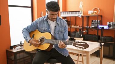 İspanyol bir adam müzik stüdyosunda gitar çalıyor.