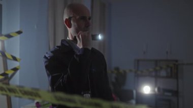 Kel dedektif el feneri, uyarı bandı ve gizemli ambiyansla olay yerini inceliyor.