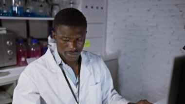 Gözlük takan Afrikalı bir bilim adamı ve laboratuarda araştırma yapan beyaz bir laboratuvar önlüğü.