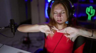 Kulaklıklı genç bir kadın geceleri neon ışıklı bir oyun odasında mikrofon kullanıyor..