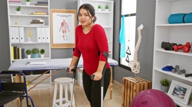 Koltuk değnekleriyle gülümseyen İspanyol kadın rehabilitasyon kliniğinde duruyor.