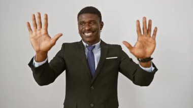 Neşeli Afro-Amerikalı takım elbiseli adam, beyaz izole edilmiş arka planda dururken parmaklarıyla bir onluk gösteriyor.