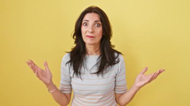 Öfkeli yaşlı Latin kadın yüksek sesle bağırıyor öfkeyle dolu esmer, dişleri dökülmüş, elleri ağzı açık bir şekilde iletişim kuruyor. Sarı arka planda izole edilmiş. Ham duyguların güçlü portresi.