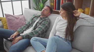 Erkek kadın televizyon uzaktan kumandalı oturma odası kanepesinden sıkılıyor.