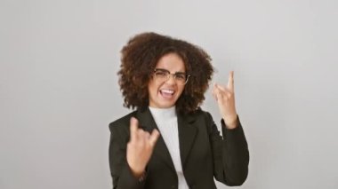 Sallanan kıvırcık saçlı İspanyol kadın ağır metal jestler yapıyor, müzik yıldızı statüsüne sahip, çılgın eğlenceli bir ifade yanıyor, beyaz arka planda izole edilmiş.