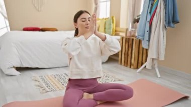 Genç bir İspanyol kadın, sakin bir yatak odasında yoga yapıyor. Huzur ve güzellik saçıyor..