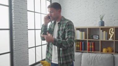 Neşeli bir kadın, modern oturma odasında akıllı bir telefonla konuşan gülen bir adamı şaşırtır..