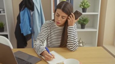 İspanyol kadın evde notlar alırken sesli mesaj dinliyor.