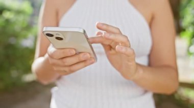 Parkta yeşil ışıklı akıllı telefon kullanan genç bir kadın.