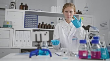 Laboratuvar ortamında kimyasalları analiz eden beyaz önlük giyen, laboratuvar aletleriyle donatılmış beyaz bir kadın bilim adamı..