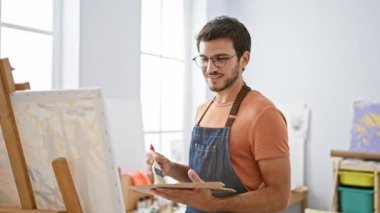 Sanat stüdyosundaki tuvale sakal ve gözlük takmış genç bir İspanyol..