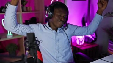 Neşeli bir adam geceleri neon ışıklı bir oyun odasında kulaklıkla dans eder.