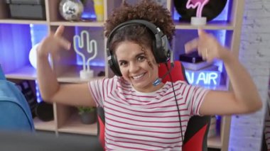 Kıvırcık saçlı İspanyol kadın oyun odasına güven saçıyor, gururu kendini mutlu bir şekilde gösteriyor.