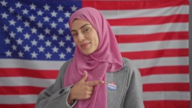 Başörtüsü takan gülümseyen bir kadın arka planda Amerikan bayrağı olan 