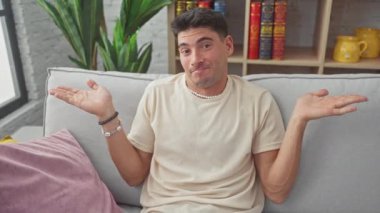 Hüsrana uğramış genç İspanyol adam yüksek sesle bağırıyor, oturma odasındaki kanepede eli ağızda sinirli sesini yükseltiyor - evde gösterilen saf duygu