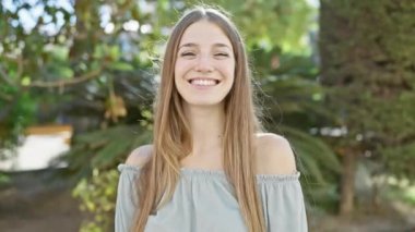 Gülümseyen genç bir kadın güneşli bir günün tadını çıkarıyor yemyeşil bir bahçede.