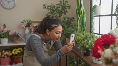 Çiçekçide akıllı telefonuyla bitkilerin fotoğrafını çeken İspanyol kadın.