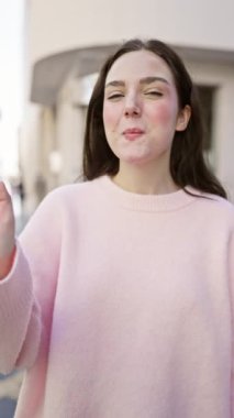 Pembe dalgalar içinde neşeli genç bir kadın güneşli bir şehir sokağında, genç enerjisi ve gündelik tarzı somutlaştırıyor..