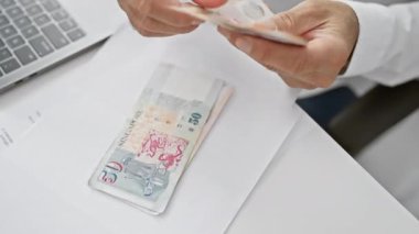 Maliye, yatırım veya iş temalarını resmeden bir ofiste tekli para sayan bir adam.