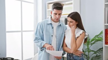 Odaklanmış iş arkadaşları, bir erkek ve bir kadın, belgeleri birlikte parlak, modern ofis ortamında değerlendirirler..