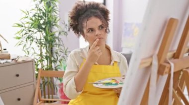 Kıvırcık saçlı mutlu İspanyol ressam stüdyoda bir fikir verdi.