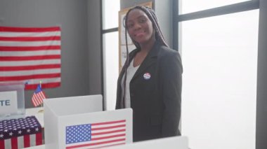 Örgülü Afrikalı Amerikalı kadın, ABD seçim sandık merkezinde bayrak sallıyor.