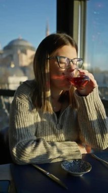 Genç bir kadın, hagia soo, istanbul manzaralı bir restoranda çay içmeyi seviyor..