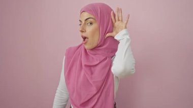 Neşeli, tesettürlü genç İspanyol kadın, elleri kulaklarına dolanmış, dedikodu dalgasına biniyor! Sağırlık caydırıcı değil, patlayan pembe bir arka plana karşı.