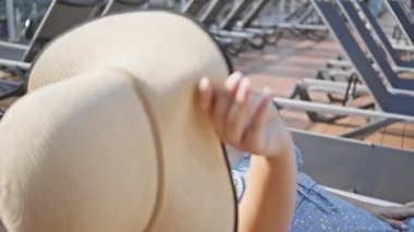 Genç bir kadın yolcu gemisindeki şezlongda dinleniyor, boş zamanlarını ve okyanus yolculuğunu simgeliyor..