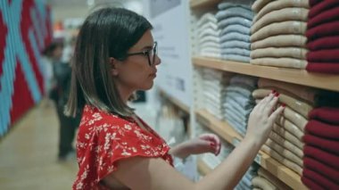 Moda tutkusu! Gözlüklü güzel İspanyol kadın perakende mağazasından şık kıyafetler seçiyor. Alışveriş merkezindeki bir butikten alışveriş yapan esmer bir kızın portresi..