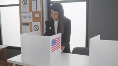 Genç bir İspanyol kadın, bir Amerikan seçiminde oy veriyor, bayrak, stant ve 'Ben oy verdim' etiketi var..