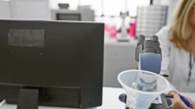 Neşeli orta yaşlı, sarışın bilim adamı bayan laboratuvarda oturuyor, dostça bir el sallıyor ve neşeli bir gülümsemeyle, olumlu bir merhaba diyor.!