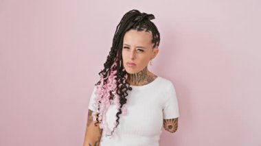 Öfkeli bir İspanyol ampüte kadın şiddetli bir tehdidi serbest bırakıyor, pembe arka planda tek başına duruyor, bir bıçak gibi eliyle havayı kesiyor.