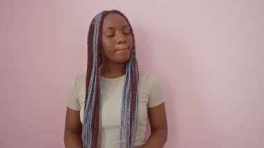 Güzel Afro-Amerikalı kadın kendine güvenerek 'para işareti' hareketi yapıyor, maaş ödemesi için şakacı bir şekilde dürtüyor; pembe arka planda tek başına duran portresi.