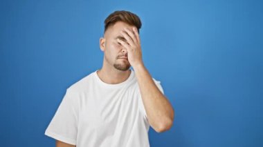 Beyaz tişörtlü İspanyol genç adam. Stres, hayal kırıklığı ve baş ağrısı gösteriyor..