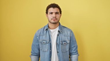 Şaşırmış genç Arap adam, yüzü şok ve huşu ile alevler içinde, sarı bir duvarın karşısında duruyor, ağzı inançsızlıkla dolu.