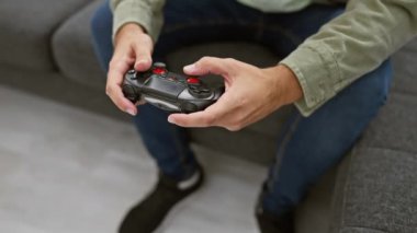 Genç sakallı bir adam, rahat oturma odasında bir kontrolörle oyun oynamaktan zevk alır. Evdeki eğlence ve eğlencenin örneğini verir..