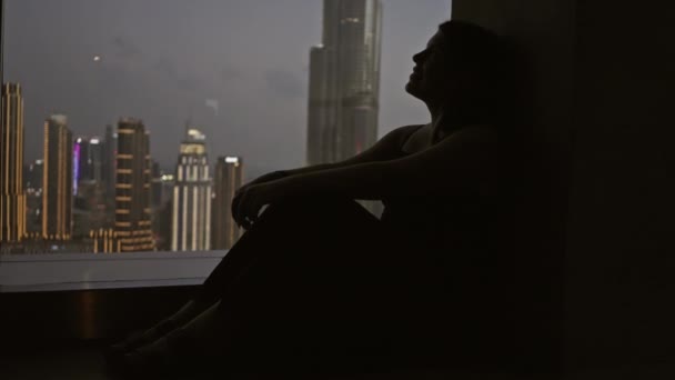 Sylwetka Kontemplacyjnej Kobiety Siedzącej Przy Oknie Widokiem Miejski Pejzaż Dubaju — Wideo stockowe