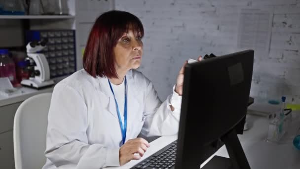 Een Gefocuste Spaanse Vrouw Een Labjas Analyseert Gegevens Een Computerscherm — Stockvideo
