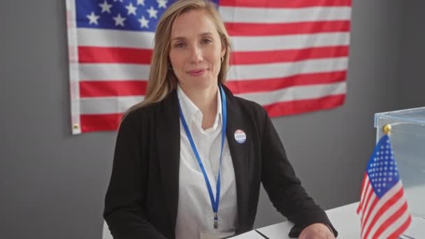 Mujer Sonriente Señalando Cámara Centro Votación Con Bandera Americana Etiqueta — Vídeos de Stock