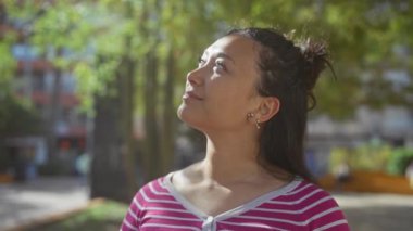 Genç İspanyol kadın, doğal güzelliğini ve günlük tarzını sergileyerek kentteki yapraklı bir parkın sakinliğinden zevk alıyor..