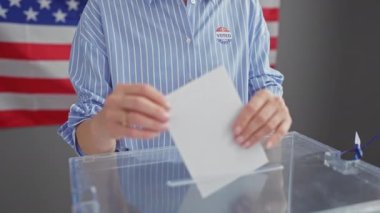 Amerikan seçimlerinde oy veren beyaz kadın, arka planda oy pusulası ve bayrağı ile, demokrasiyi ve vatandaşlık görevini sembolize ediyor.