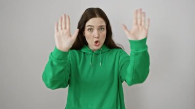 Hüsrana uğramış genç bir kadın, süveter giymiş ve beyaz izole bir arka planda duruyor, el hareketleriyle 'dur' işareti veriyor, sinir bozucu ve hayal kırıklığını iletiyor..