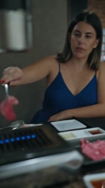 Modern yemek deneyimi, genç bir kadının elleri Japon restoranında ızgarada lezzetli wagyu bifteği pişiriyor, lezzetli kızarmış etin tadını çıkarıyor.